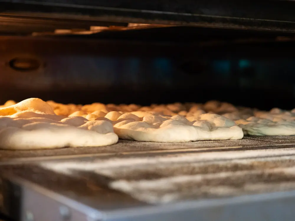 Teglie di pinse in cottura nel forno del laboratorio