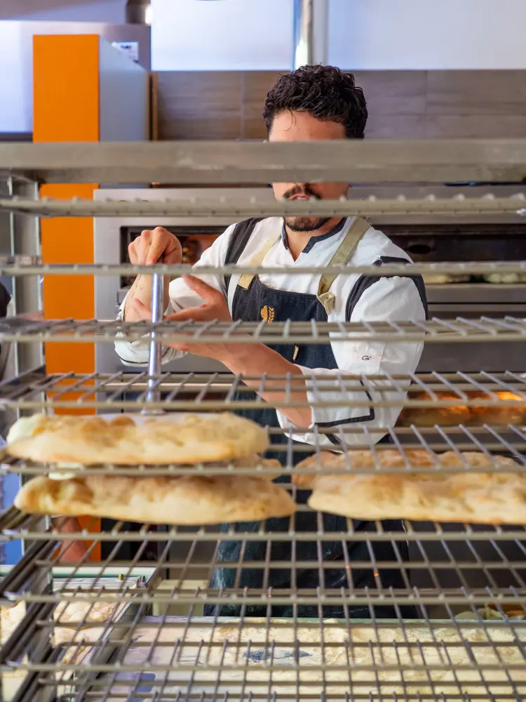 Un artigiano di Basi del Gusto tra i carrelli di basi appena sfornate